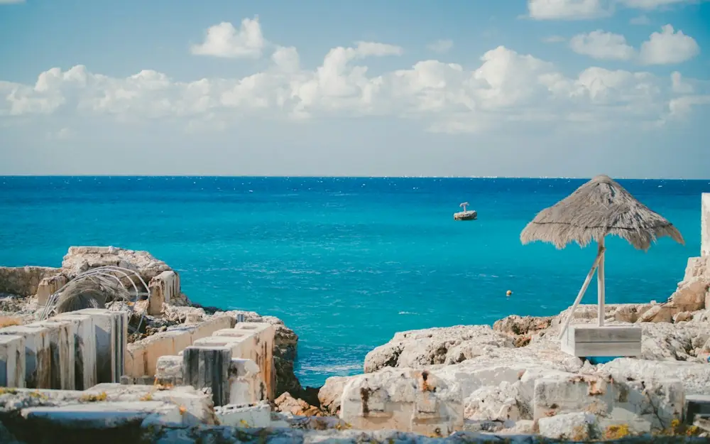 thatch parasol near ruins on island and sea at the distance during day