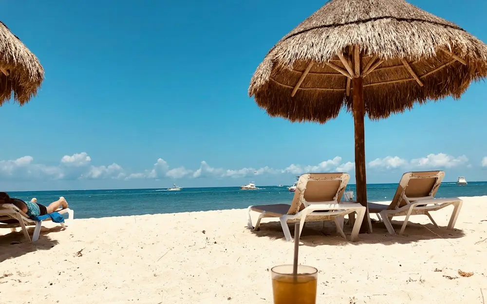 brown parasol and two beach chairs on beach sand